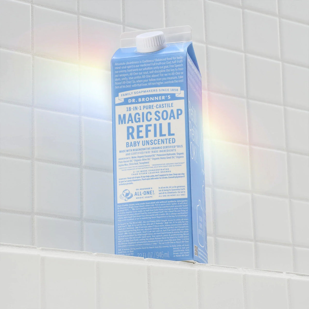 Carton of Dr. Bronners 18 in 1 Pure Castile Magic Soap Refill sits on white tiled shelf, text highlighting organic, eco friendly uses, and sustainability benefits under soft lighting [32 oz]